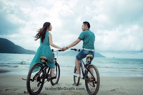 e615211d335aa19c7f9a1a65d3038f91 Two people on bikes at the beach, holding hands